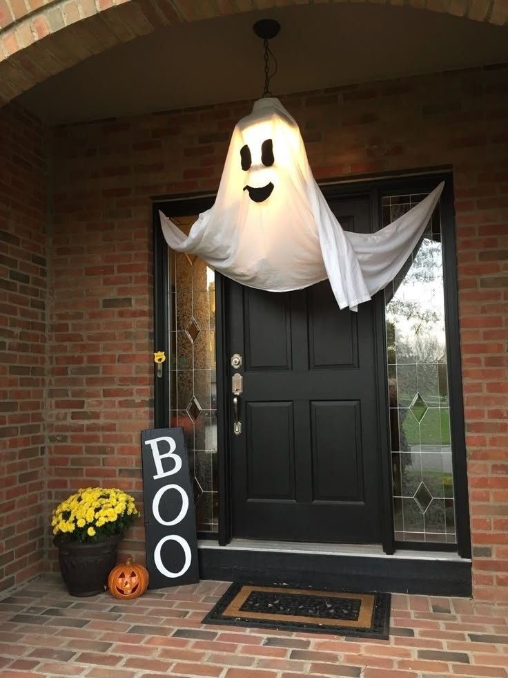 Front porch Halloween decor with hanging ghost and pumpkin display