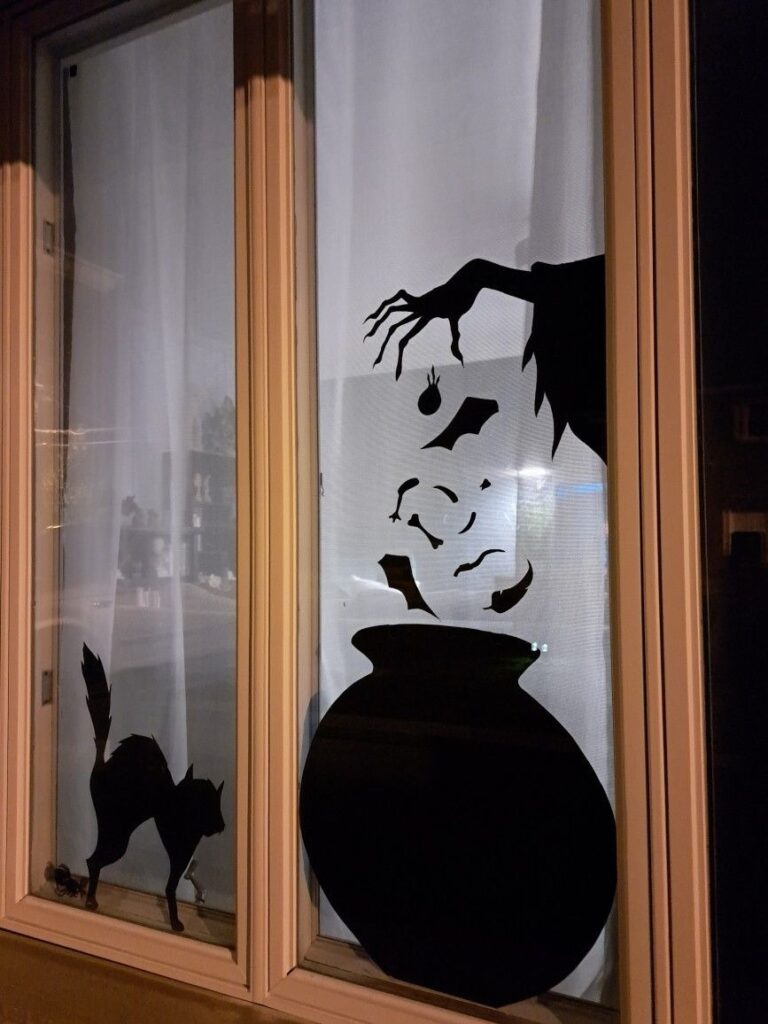 Halloween window silhouette with witch cauldron and black cat