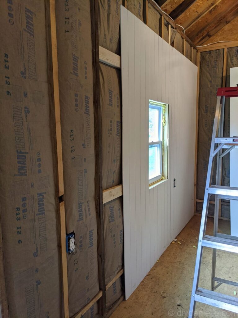 Installing wall insulation and paneling during home renovation project
