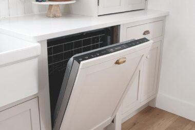 Built-in dishwasher in modern white kitchen with wood flooring